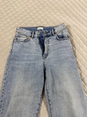 Ljusblå raka jeans från Lindex - Säljer ett par ljusblå jeans från Lindex med klassisk femficksmodell och raka ben. Jeansen har hög midja, bälteshällor och är gjorda i ett slitstarkt denimtyg. Perfekta för en avslappnad och trendig look.