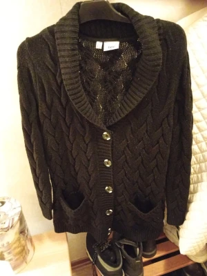 Svart kabelstickad kofta från bpc stl 44/46 - Svart kabelstickad kofta från bpc med stora knappar framtill och två fickor. Koftan har bred krage och ribbstickade detaljer vid ärmslut och nederkant. Perfekt för lager-på-lager och en cool look. Nyskick stl 44/46