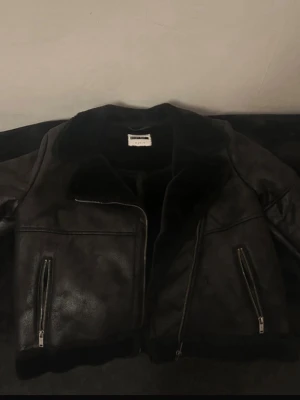 Svart teddyjacka från Vero mode - Snygg svart jacka från vero mode med mjukt foder och bred krage. Jackan har två dragkedjeförsedda fickor framtill och en rak, perfekt för våren och hösten.