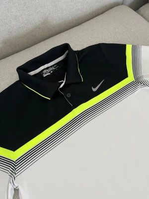 Nike Golf Dri-Fit pikétröja svart/vit - Nike Golf Dri-Fit pikétröja i svart och vitt med neongula detaljer och tunna svarta ränder. Klassisk krage med knappslå och diskret Nike-logga på bröstet. Tillverkad i funktionsmaterial som andas, perfekt för sport och träning. Kom med ett rimligt pris så kör vi på det🥰