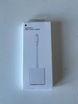 Apple Lightning till USB 3 adapter - Apple Lightning till USB 3 Camera Adapter i vit färg. Perfekt för att koppla in USB-tillbehör som kamera eller minneskort till din iPhone eller iPad. Adapter med Lightning-kontakt och USB-port, tillverkad i plast med stilren och enkel design.