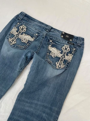 Lågmidjade bootcut miss me jeans - Supersnygga och trendiga😍 Storlek W34 inte EU34!!! Midja 46x2 cm, gren 23 cm o innerben 87 cm. Inringad fläck på knät samt slitna i skrevet vilket syns på bilderna (kolla noga så det inte sker några missförstånd). Saknas också en av fyra skruvar på grejen i midjan. Pga defekterna är priset lågt i jämförelse med andra likadana!