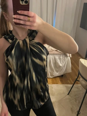 Svart och beige ärmlös blus - Säljer en snygg ärmlös blus med svart och beige mönster. 