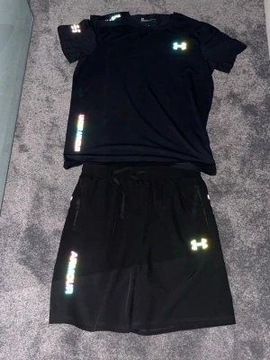 Svart Under Armour Set - Svart under armour set, shorts och tröja med svart färg och märket är reflex