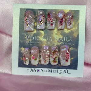 SakuraDrip (S);Medium Square - Handgjorda press-on naglar i medium lång squareform med nuderosa bas, dekorerade med sakurablommor, pärlor, hjärtan och 3D linjer. Naglarna har en glansig finish och detaljer i rött, rosa och vitt. Perfekt för dig som vill ha unika och kreativa naglar.S: 15 mm, 11,5 mm, 12 mm, 11 mm, 9 mm 