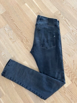 Grå jeans från replay  - Snygga mörkgråa jeans från replay  med klassisk femficksdesign och svart läderpatch bak i midjan. Jeansen har raka ben och diskret broderad detalj på bakfickan. Jeansen är 32/34. Jeansen är i stretchigt denim så väldigt sköna! Prutmått finns vid snabb affär!!