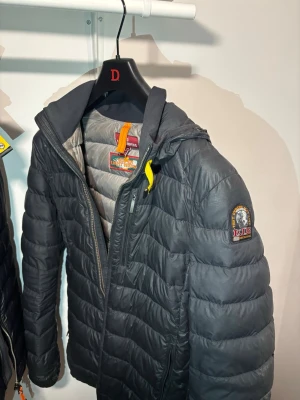 Svart dunjacka från Parajumpers - Säljer en svart dunjacka från Parajumpers med quiltad design och gul detalj vid kragen. Jackan har dragkedja framtill, hög krage. Det har dock 3 st jätte små hål, skriv så kan jag skicka bild. Annars en perfekt jacka för vår och kalla sommar dagar.