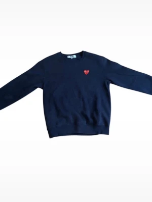 Svart sweatshirt Comme des Garçons Play - Cool svart sweatshirt från Comme des Garçons Play med det ikoniska röda hjärtat broderat på bröstet. Tröjan har rund halsringning och är gjord i mjukt bomullsmaterial. Perfekt för en avslappnad och trendig stil. Storleken är L men passar även som M, har du några frågor är det bara att höra av sig.