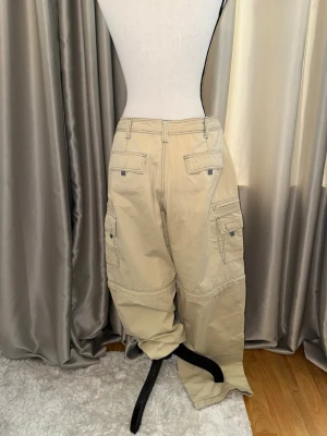 Y2k  cargobyxor  - Säljer ett par beige cargobyxor med flera stora fickor på sidorna och bak. Byxorna har en loose fit. 