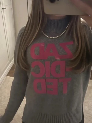 Grå stickad tröja med rosa text - Säljer denna jättesnygga tröja från Zadig💞💞(skriv gärna vid fler bilder osv) postar imorgon för ska posta fler paket då😊