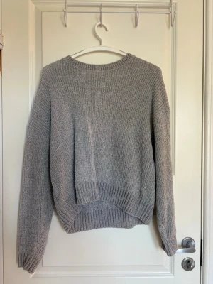 Grå stickad tröja - Mysig grå stickad tröja med rund halsringning och ribbade muddar vid ärmslut och nederkant.