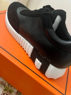 H skor  - Snygga svarta sneakers  med en unik, räfflad vit och svart sula. Skorna har en kombination av slätt läder och mockadetaljer, samt klassisk snörning. Perfekta för dig som gillar exklusiv och modern design.