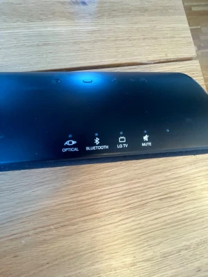 LG svart trådlös soundbar - Stilren svart soundbar från LG med Bluetooth och optisk anslutning. Perfekt för att koppla till LG TV och har även mute-funktion. Lång och smal design i matt plastmaterial som passar snyggt under TV:n.