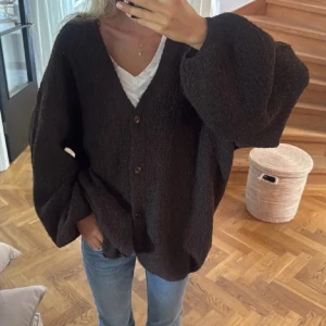 Brun oversized kofta med v-ringning - Mysig brun kofta med v-ringning och knappar framtill. Koftan har en oversized passform och vida ärmar, vilket ger en avslappnad och trendig look. 