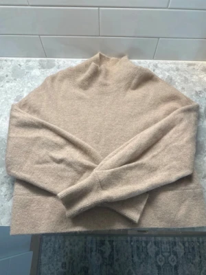 Beige ull polotröja - Mysig beige ull polotröja med lång ärm. Tröjan har en avslappnad passform och är perfekt för lager-på-lager-stil.