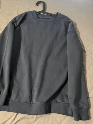 Mörkblå sweatshirt från 157 - En basic mörkblå sweatshirt från 157 med rund halsringning och ribbade muddar vid ärmslut och nederkant. Perfekt för en avslappnad och stilren look. Tillverkad i mjukt material som känns skönt mot huden.