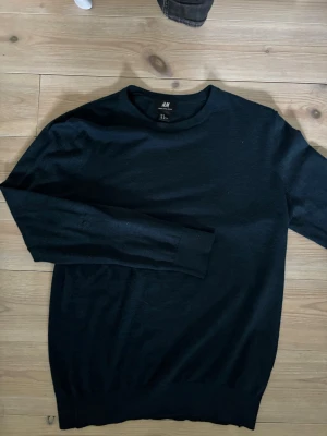 Blå merinoulltröja från H&M - Säljer en blå stickad tröja från H&M i mjuk merinoullsblandning. Tröjan har rund halsringning, långa ärmar och ribbade muddar vid ärmslut och nederkant. Perfekt för lager på lager och enkel att matcha med olika outfits.