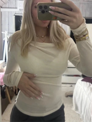 Krämvit off shoulder  topp - Säljer en krämvit, tight långärmad topp med offshoulder-design. Toppen har en mjuk, stretchig känsla och sitter figurnära. Perfekt för dig som gillar stilrena och enkla plagg med en twist.
