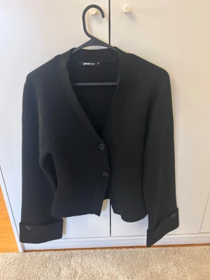 Svart kofta från Gina Tricot - Stilren svart kofta från Gina Tricot med två knappar framtill och breda armar. Nästan aldrig använd och väldigt bra skick. Skriv för fler frågor och bilder. 