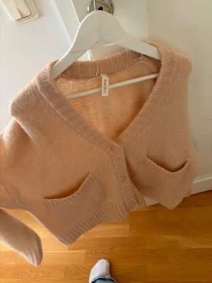 Kappahl kofta med knappar  - Säljer denna jätte fina populära tröjan ifrån Kappahl som inte säljs längre. Den är i bra skick. Den är i storlek M/L står de på lappen men om man vill ha den mer oversized så passar den säkert mindre storlekar. Men då sitter den lösare såklart. 2 och 3 bilden var de ganska starkt som ljud vilket gjorde färgen lite mer beige. Men kolla noggrant på bild 1 så ser du hur färgen är. Material är polyester,WOOL, Mohair