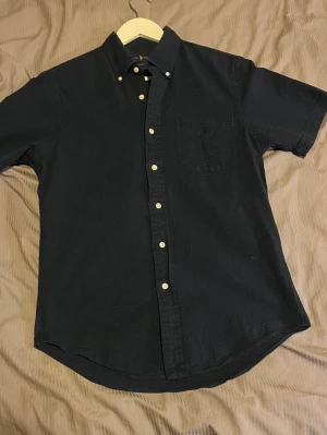 Polo Ralph Lauren mörkblå skjorta – strl M – äkta –  - Säljer en mörkblå Polo Ralph Lauren skjorta i storlek M. Den är endast använd lite och är i mycket fint skick utan några defekter.  Nypris ligger på 2295 kr, säljer den för 1649 kr eftersom den tyvärr inte kommer till användning och jag vill få något för den istället.  Äkta Ralph Lauren  Storlek M  Mörkblå  Använd få gånger  Perfekt för sommaren  Snygg både till vardag och finare tillfällen  En väldigt stilren skjorta som passar perfekt till sommaren tack vare den mörkblå färgen och den klassisk