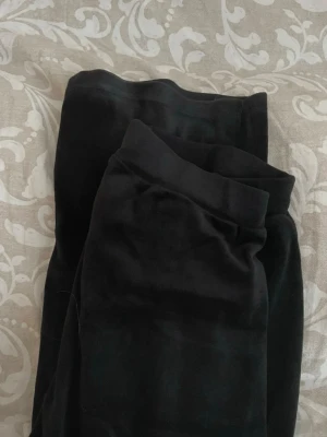 Svarta utsvängda mjukisbyxor  - Säljer ett par svarta mjukisbyxor med utsvängda ben. De har en hög midja och är gjorda i ett mjukt, stretchigt material som känns skönt mot huden. 