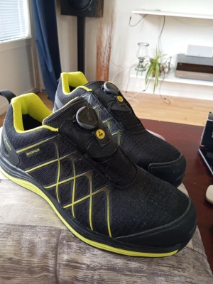 Svarta skyddsskor med BOA-snörning - Säljer ett par svarta skyddsskor från Sievi med neongula detaljer och BOA-snörning. Skorna har en sportig look med meshmaterial och vattentätt membran. Sulan är svart med neongula inslag och insidan är fodrad i gult. Perfekta för dig som gillar stil och funktion.  Helt nya Nypris 1900:-
