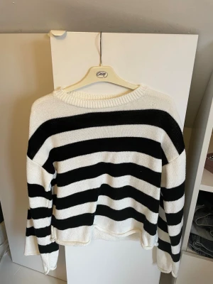 Randig stickad tröja svart/vit - Säljer en stickad tröja med breda svarta och vita ränder. Tröjan har rund halsringning, långa ärmar och avslappnad passform. Perfekt för dig som gillar klassisk och enkel stil. Köpt på vinted så lamporna med storlek fanns inte med , men jag är S/M och den passar mig bra! 