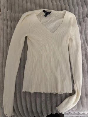 Vit ribbad stickad tröja V-ringad - Säljer en vit ribbad stickad tröja från Gina Tricot med V-ringning och långa ärmar. Tröjan har en slim passform och är perfekt för lager på lager eller som den är. Enkel och stilren design som passar till det mesta. Storlek S, använd 1 gång. Den är från vero Moda.