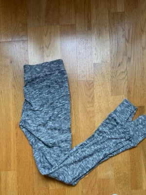 Gråmelerade leggings med hög midja - Säljer ett par gråmelerade leggings med hög midja och smal passform. Mjukt och stretchigt material som sitter skönt på kroppen. Perfekta till en avslappnad look eller när du vill vara bekväm.