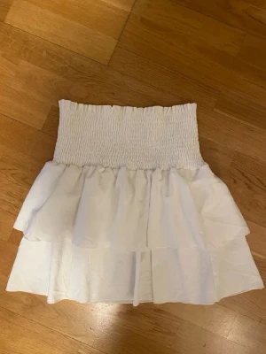 Vit volangkjol  - Söt vit kjol med bred smock i midjan och dubbla volanger. Köpt i Spanien!! Använd 1 gång 