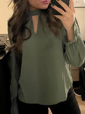 Grön blus med cut out-detalj - Grön blus med lång ärm och trendig cut out-detalj vid halsen. Blusen är från Vero Moda i storlek xs o är i nyskick ☀️