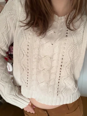 Vit kabelstickad tröja - Säljer en krämvit kabelstickad tröja med rund hals och långa ärmar. Tröjan har ett klassiskt flätmönster framtill och ribbade muddar vid ärmslut och nederkant. Perfekt för lager på lager och en chill look. Stickad tröja ifrån Lindex, storlek 170 men passar perfekt på mig som är xs