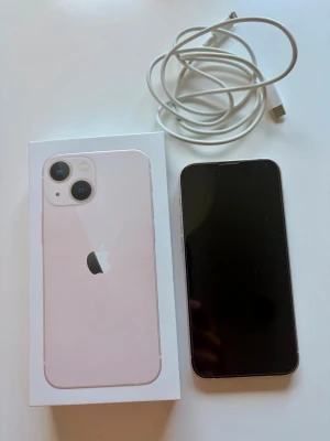 Ljusrosa iPhone 13 med tillbehör - Säljer en iPhone 13 mini med 128 GB lagring i rosa färg.  Telefonen har inga repor eller andra skador då den haft skal och skärmskydd hela tiden. Batterihälsa 85% Kartong och min laddarsaldd medföljer då jag inte använder laddaren längre.  Telefonen är Olåst och Nollställd och redo för ny användare.   Perfekt som present då den är välbevarad med kartong.  Pris: 2800kr