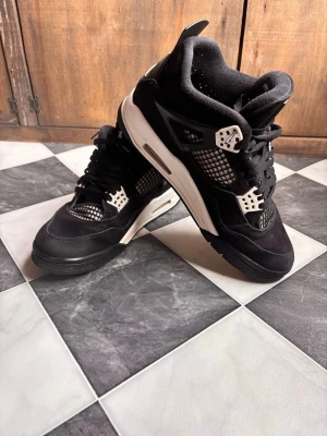 Svarta Air Jordan 4 Retro sneakers thunder white - Säljer ett par svarta Air Jordan sneakers retro design. Skorna har en vadderad plös med Air Jordan-logga och är tillverkade i svart mocka. En liten skada på v.fram men går att fixa - därför sänker jag priset.