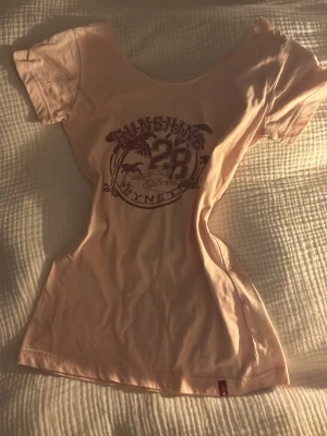 Ljusrosa t-shirt från Bynet - Ljusrosa t-shirt från Bynet med tryck framtill som visar texten 'Sunshine 28 Paradise Island'. T-shirten har rund halsringning och korta ärmar. Aldrig använd och köpte på vinted. 🩷