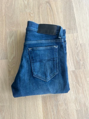 Tiger of Sweden jeans (slim fit) - Snygga mörkblå jeans i slim fit-modell med klassisk femficksdesign och kontrastsömmar. Jeansen har en svart patch bak i midjan och är tillverkade i ett mjukt denimtyg som ger en skön känsla. Perfekta till vardagslooken.