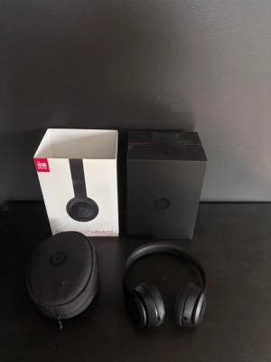 Svarta Beats Solo3 Wireless hörlurar - Stilrena svarta over-ear hörlurar från Beats, modell Solo3 Wireless. Trådlösa med upp till 40 timmars batteritid. Kommer med originalförpackning och ett smidigt hårt fodral. Hörlurarna har en modern design med mjuka öronkuddar i konstläder och justerbar bygel.