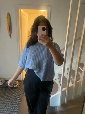 Ljusblå ribbad topp med kort ärm - Säljer en ljusblå ribbad topp med kort ärm och avslappnad passform. Toppen har en enkel, stilren design och är perfekt att styla till både jeans och kjol. Materialet känns mjukt och bekvämt mot huden.