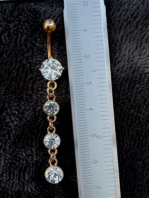NY oanvänd Navelpiercing med hänge | Kirurgiskt stål | Vita stenar  - 💕30% Bundle-rabatt vid köp av minst 2 artiklar. ⭐️NY oanvänd piercing i kirurgiskt stål; rostfritt och säkert för läkta piercingar.                               📏MÅTT ⭕️Stavens längd: 10mm ⭕️Stavens tjocklek: 1,6mm ⭕️Smyckets totala längd: 60mm                                                                         🤍Färger: Guld och vit                                                           💌Skickas spårbart via Plick SafePay.