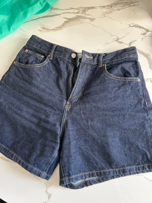 Jeansshorts Gina tricot - Slutsålda denimshorts från Gina tricot, i mörkblå jeans, med gula detaljer