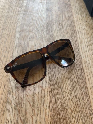 Bruna solglasögon Ray-Ban Boyfriend - Säljer ett par klassiska solglasögon från Ray-Ban i brunmelerad färg. Snygg tidlös design med Ray-Ban-logga på bågen. Tillverkade i Italien och perfekta för soliga dagar.