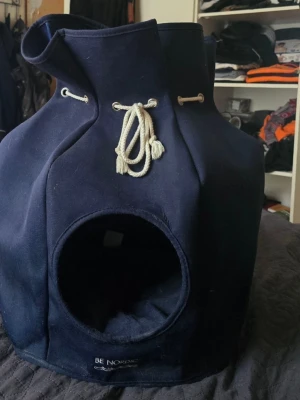 Trixie hundkoja ( för mindre hundar) - Säljer en blå kattkoja från Trixie, modell BE NORDIC. Gjord i kraftigt tyg med snördetaljer och rund öppning framtill. Perfekt som mysig plats för din katt att krypa in i. Snygg design med maritim känsla. Material polyester. Kan tvättas i 40 grader .väldigt fint skick, min hund växte sig för stor snabbt