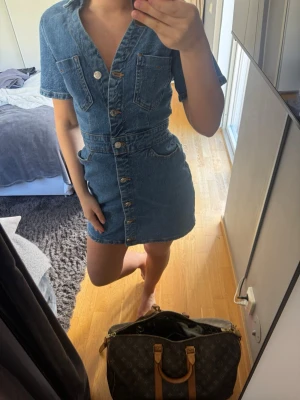 Zara Jeansklänning - Snygg kort jeansklänning med knappar framtill och två bröstfickor. Klänningen har korta ärmar, markerad midja. Sitter så snyggt!!!