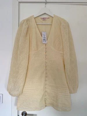 Ljusgul blommig klänning från Gina Tricot - Superfin populär SLUTSÅLD ljusgul kortklänning från Gina Tricot young 14+ med broderat blommönster, v-ringning och långa puffärmar. Tyvärr för liten för mig. HAR ÄVEN EN I STORLEK XS PÅ MIN PROFIL🌸💞