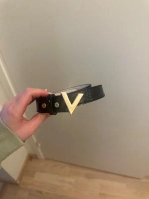 Svart skärp från Valentino med gulddetalj - Svart skärp från Valentino med ett V-format spänne i guld. Passar någon som har S/M