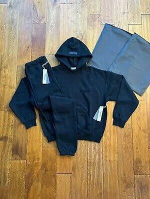 Svart loungewear set med hoodie - Säljer ett svart loungewear set från Essentials med matchande hoodie och byxor. Hoodien har luva och ribbade muddar, byxorna har resår i midjan och benslut. Perfekt för chill dagar hemma. Materialet känns mjukt och bekvämt.