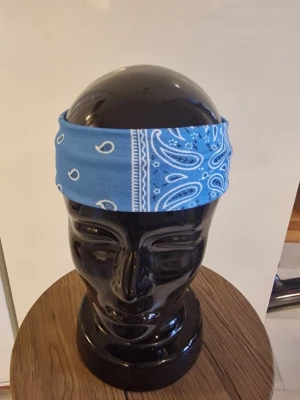 Bandanas/hårband cachewnöt blå - Bandanas/hårband cashewnöt. Elastisk. 23,5 cm huvud. Bredd 6 cm. Trikåtyg. Polyester.