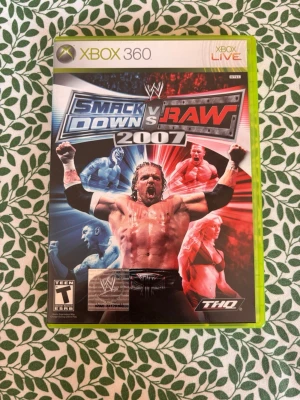 WWE SmackDown vs Raw 2007 Xbox 360 - Wrestlingspelet WWE SmackDown vs Raw 2007 till Xbox 360. Omslaget har en mix av blått och rött med flera kända brottare. Spelet är i klassisk plastfodral med Xbox 360-design och är utvecklat av THQ. Perfekt för dig som gillar action och wrestling.