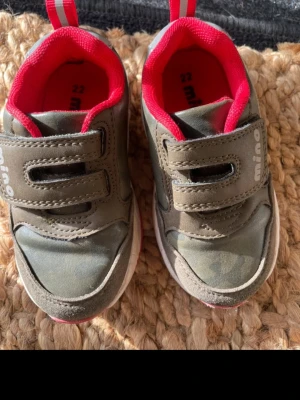 Gröna sneakers med kardborreband - Snygga gröna sneakers med dubbla kardborreband och röda detaljer på insidan samt vit och röd sula. Skorna har en sportig look och är perfekta för dig som gillar bekväma och stilrena sneakers. Storlek 22. Barn 